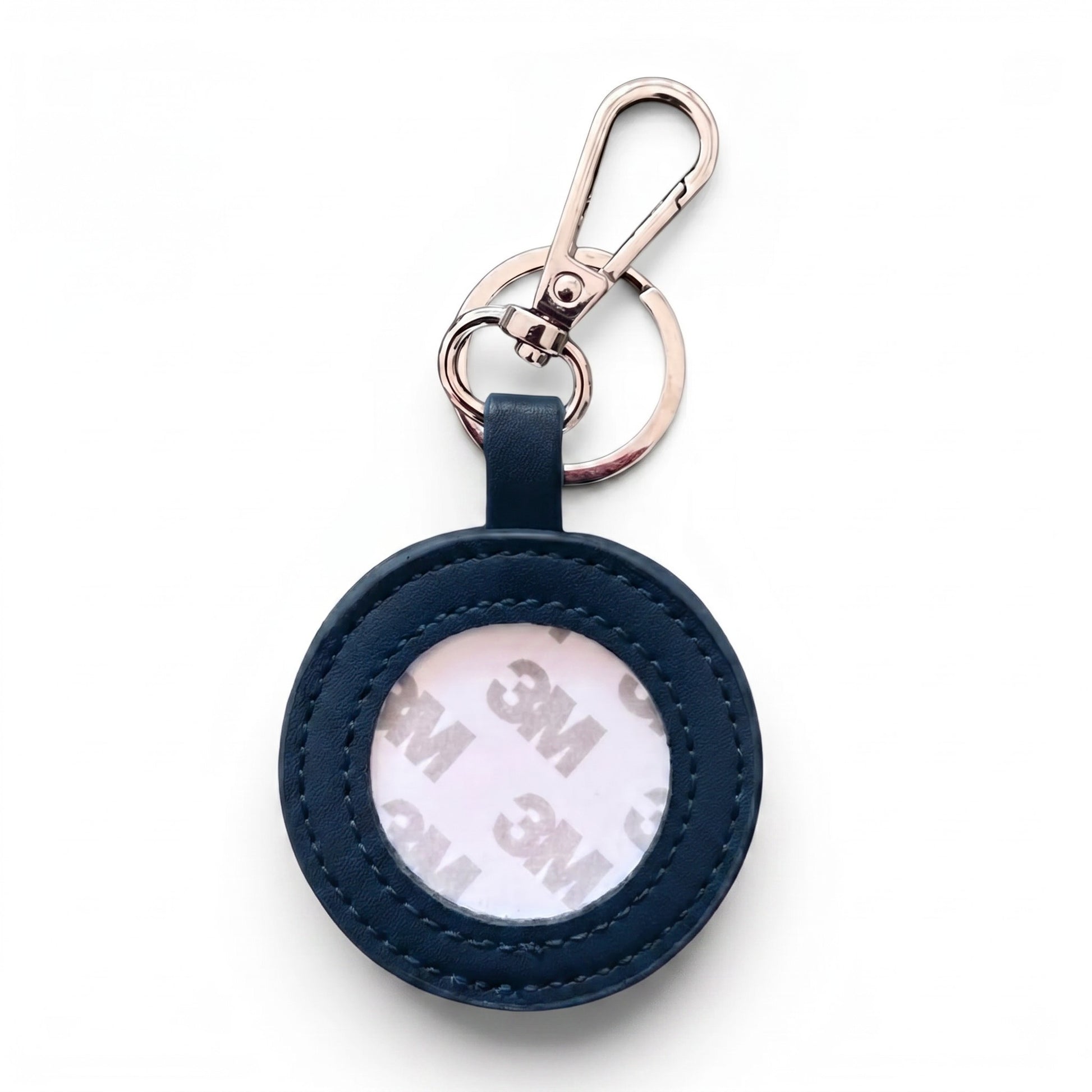 A round navy blue leather keychain holder with a clear window showing a 3M adhesive backing, attached to a silver metal carabiner and split ring, on a white background.