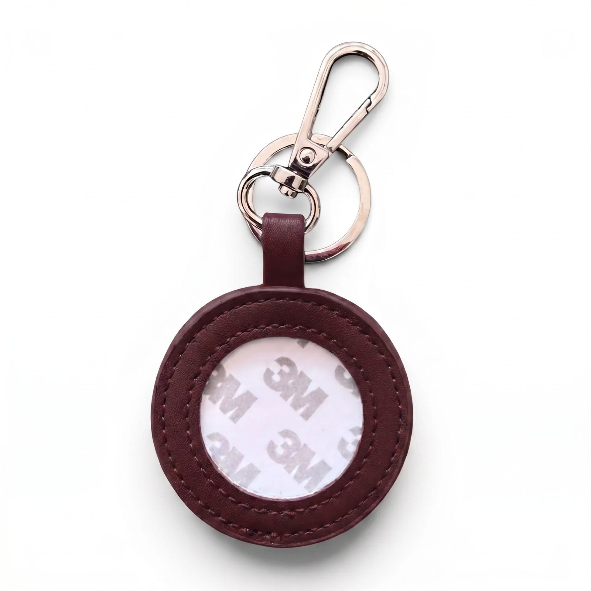 A round red leather keychain holder with a clear window showing a 3M adhesive backing, attached to a silver metal carabiner and split ring, on a white background.